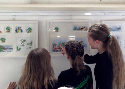Kinder schauen Zeichnungen vom Singfrosch an